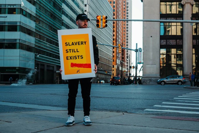 Man holding a sign that says slavery still exist